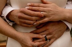 the bride and groom are holding each other's hands while they hold their wedding rings