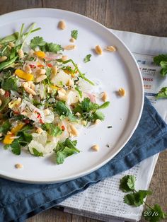 a white plate topped with salad on top of a blue cloth next to a napkin