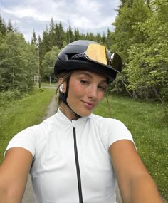 a woman riding on the back of a bike down a road next to a forest