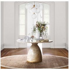 a round table with vases and flowers on it in front of an arched window