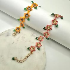 the bracelet is decorated with colorful beads and gold chains on a white marble surface next to a folded napkin