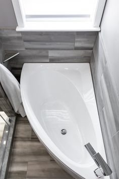 a white bath tub sitting in a bathroom next to a window