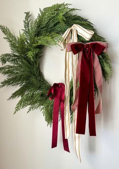 a wreath with red and white ribbons hanging from it's side next to another wreath