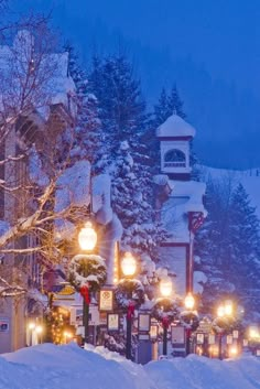 a snowy street with lots of lights on it and snow covered trees in the background