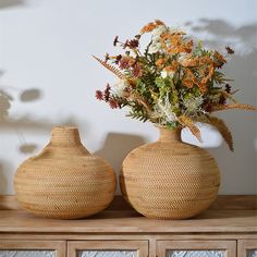 two vases with flowers in them sitting on a table