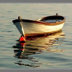 a small white boat floating on top of a lake next to a red buoy