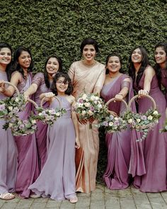 a group of women standing next to each other holding bouquets in their hands and smiling