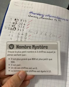 a person is holding up a card with numbers on it in front of a notebook