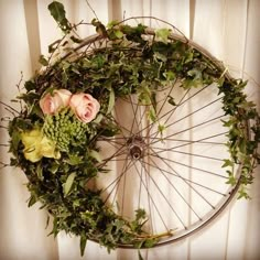 a bicycle wheel with flowers and greenery on the rim is mounted to a wall