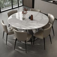 a white table with chairs around it in a room that has large windows and lots of light