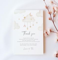 a thank card with clouds and stars hanging from it's sides next to flowers