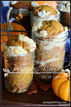 three jars filled with desserts sitting on top of a wooden table next to pumpkins