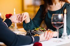 two people sitting at a table with plates of food and candles in front of them