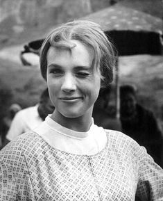 a black and white photo of a young woman with an umbrella in the back ground