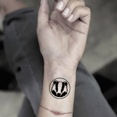 a person's wrist with a black and white logo on the left side of their arm