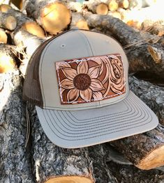 A tan and brown Richardson Trucker hat decked out with a sunflower and some vines on a leather patch! These Richardson  hats are super comfortable and have an adjustable snap back.  PLEASE READ: This item is for pre-ordering, and is made to order! Once purchased, this item will take approximately two weeks to re-create. Item will be a close replica, but each one will have slight variances in color, carving, etc. as I am not perfect, and leather is not perfect either! *All of HCL's leather produc Brown Country Cap Style Hat, Brown Country Cap Hat, Brown Trucker Hat For Country Events, Brown Trucker Hat With Curved Brim For Country Events, Brown Curved Brim Trucker Hat For Country Events, Brown Country Style Cap, Brown Country Style Trucker Hat, Country Style Brown Trucker Hat With Curved Brim, Country Style Brown Trucker Hat