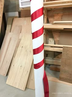 a large red and white pole with a ribbon on it in a room full of wood planks