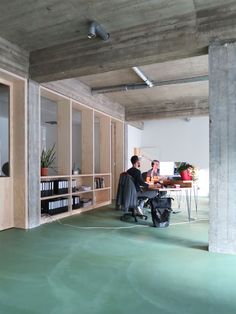 two people are sitting at a desk in an office with bookshelves and shelves