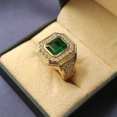 an emerald and diamond ring in a box