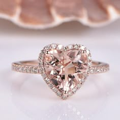 a heart shaped pink diamond ring on top of a shell