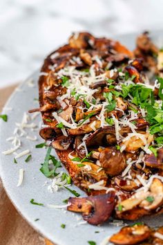 a white plate topped with mushrooms and parmesan sprinkled cheese on top of it