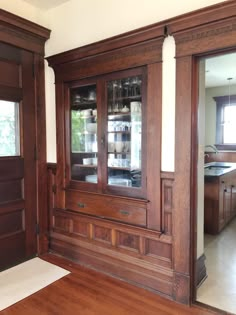 an empty room with wood paneling and glass front cabinets on the wall, along with hardwood flooring