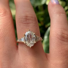 a woman's hand with a ring on it and an oval shaped diamond in the middle