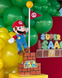 a nintendo mario birthday cake on display with balloons in the background and a super mario decoration