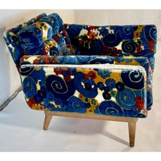 a blue and yellow patterned chair against a white wall