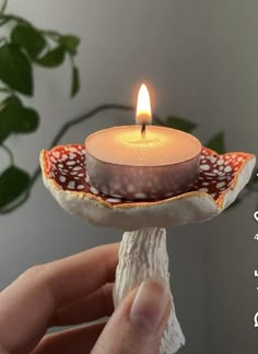 a hand holding a lit candle in a bowl