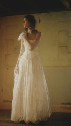 a woman in a long white dress is standing with her hands on her hips and looking off to the side