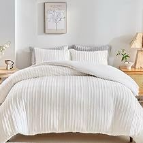 a bed with white comforter and pillows in a room