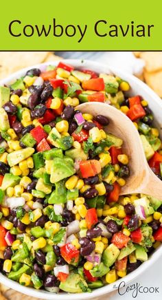 a white bowl filled with black beans, corn and avocado salad next to tortilla chips