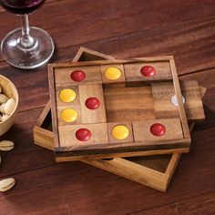 a wooden board game set next to a glass of wine and some almonds on a table