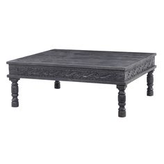 an old wooden coffee table with carvings on the top and legs, in grey wood