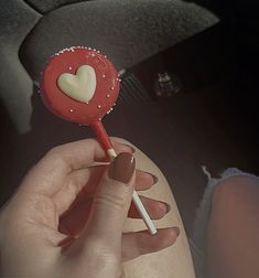 a person holding a heart shaped lollipop in their hand