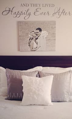 a bed with two pillows on top of it next to a wall mounted photo and the words happily ever after