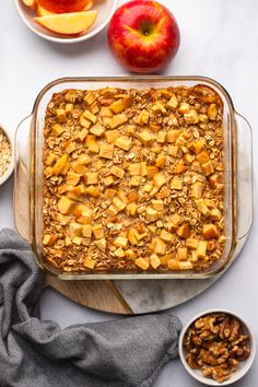 an apple and oatmeal dessert in a glass dish on a marble table