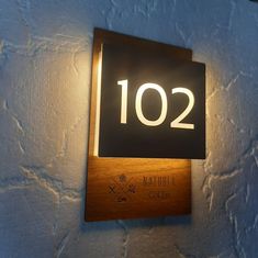 a wooden plaque with the number 120 on it is lit up by a dim light