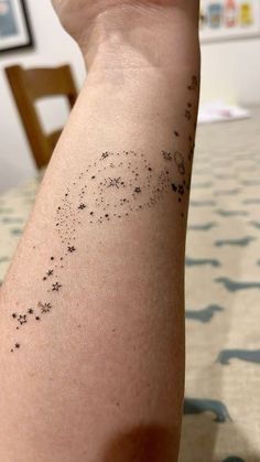 a person's arm with black ink on it and stars all over the arm