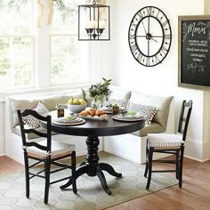 a black table topped with plates and bowls filled with food next to a clock mounted on the wall