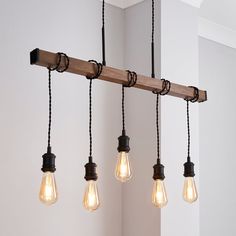 five light bulbs hanging from a wooden beam in a room with white walls and flooring