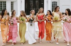 a group of women standing next to each other in front of a white building holding bouquets