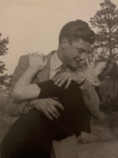 an old black and white photo of a man holding a woman