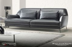 a black leather couch sitting on top of a white rug