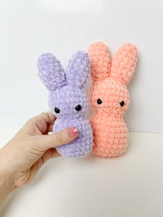 two small crocheted stuffed animals are being held by a person's hand