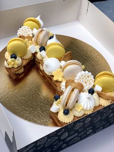 a cake in a box is decorated with yellow and white icing, blueberries, and other desserts