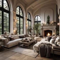 a living room filled with lots of furniture next to large windows and a fire place