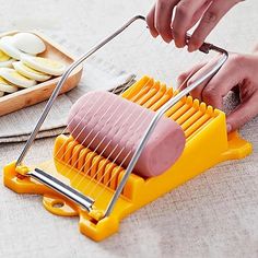 a person using a potato slicer to cut up potatoes on a table with other foods in the background