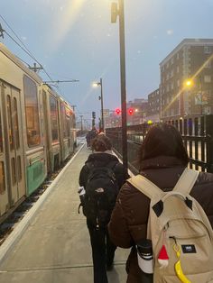 people walking on the sidewalk next to a train